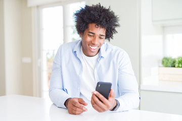 Fototapeta na wymiar African American man using smartphone with a happy face standing and smiling with a confident smile showing teeth