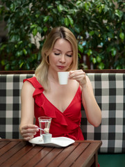 Young Caucasian  woman spending time in street cafe with cup of Turkish coffee.