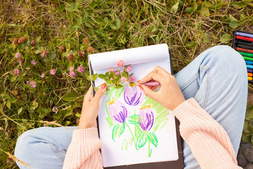 Girl draws clover flower with crayons. Talent inspiration creation and self expression concept