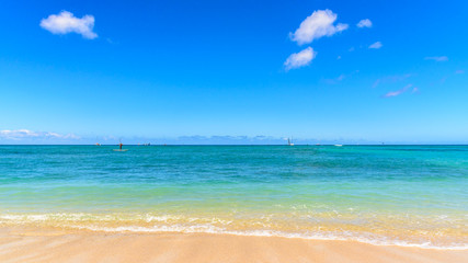 Fototapeta na wymiar Colourful shore of a tropical beach. The sand is golden yellow, and the sea id a clear aqua blue. The beach is Waikiki beach, Hawaii