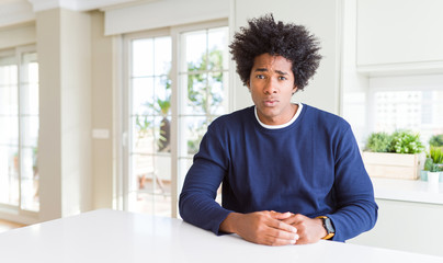 Young african american man wearing casual sweater sitting at home skeptic and nervous, frowning upset because of problem. Negative person.