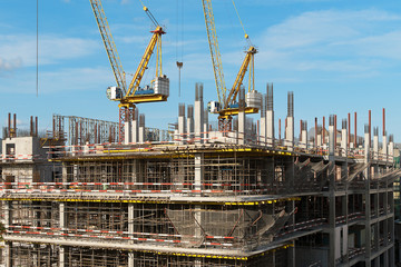 The construction of a multi-storey building. Two construction cranes on a building construction....