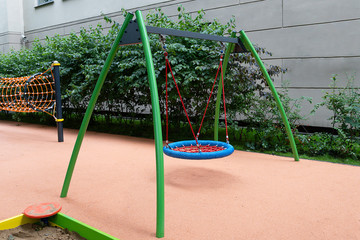 Children's playground with a rope circle on a swing. Functional trainer made of ropes for children. Red spider web made of rope on a blueю