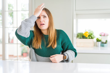 Young beautiful plus size woman wearing casual striped sweater surprised with hand on head for...