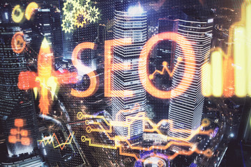SEO hologram on city view with skyscrapers background double exposure. Search optimization concept.