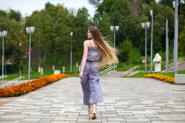 Young beautiful woman in gray dress walking on the summer street