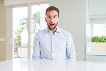 Handsome business man afraid and shocked with surprise expression, fear and excited face.