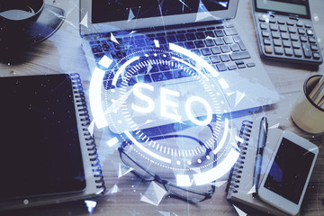 Double exposure of table with computer and seo drawing hologram. Search optimization concept.