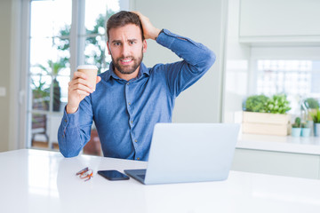 Handsome man working using computer laptop and drinking a cup of coffee stressed with hand on head, shocked with shame and surprise face, angry and frustrated. Fear and upset for mistake.
