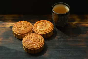 three Chinese moon cakes with green tea in a small cup