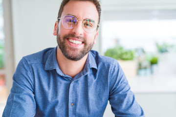 Handsome man wearing glasses and smiling relaxed at camera