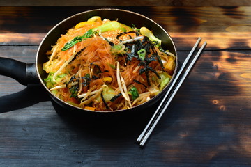 Korean style glass noodles with chili, seaweed, beansprouts with metal chopsticks next to it