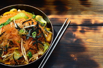 Korean style glass noodles with chili, seaweed, beansprouts with metal chopsticks next to it