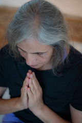 Senior Indian woman with grey hair and glowing skin, meditating in the morning. 