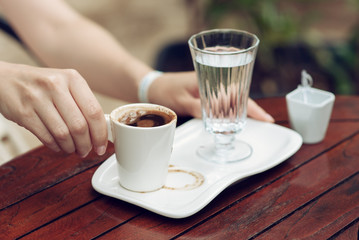 Close up of beautiful female hands holding white cup of coffee.