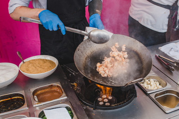 Chef tosses shrimps in a pan, grilling them