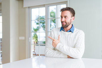 Fototapeta premium Handsome man wearing casual sweater cheerful with a smile of face pointing with hand and finger up to the side with happy and natural expression on face