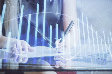 A woman hands writing information about stock market in notepad. Forex chart holograms in front. Concept of research.