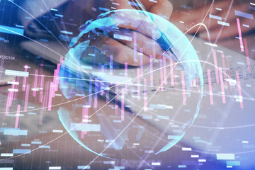 A woman hands writing information about stock market in notepad. Forex chart holograms in front. Concept of research. Multi exposure