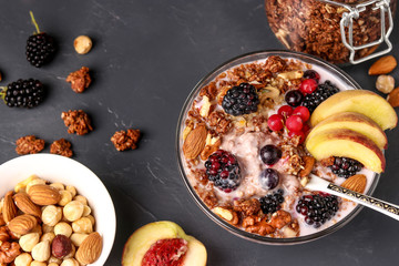 Granola crispy honey muesli with natural yogurt, fresh berries and fruit, chocolate and nuts in a glass bowl against a dark background, horizontal orientation, top view
