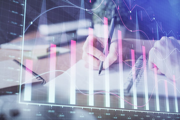 Financial forex graph drawn over hands taking notes background. Concept of research. Multi exposure