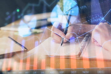 Financial forex graph drawn over hands taking notes background. Concept of research. Multi exposure