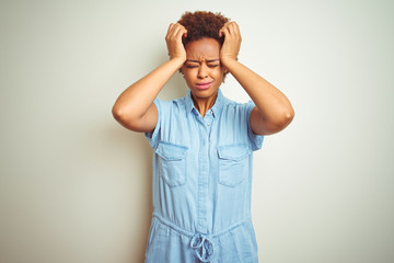 Young beautiful african american woman with afro hair over isolated background suffering from headache desperate and stressed because pain and migraine. Hands on head.