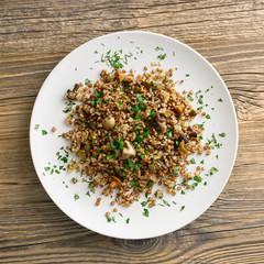 buckwheat porridge with mushrooms, onion, and salted cucumber decorated with dill and parsley