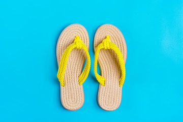 Eco yellow bamboo flip flops on blue background Flat lay, top view. Zero waste, plastic free, holiday, summer, vacation concept. 