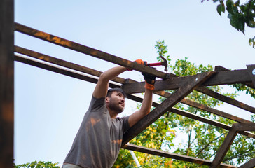 Man building wooden roof working with hammer