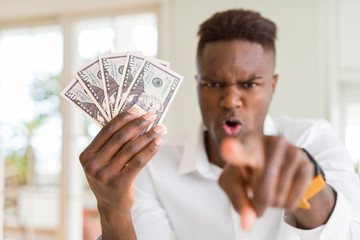 African american man holding fifty dollars bank notes pointing with finger to the camera and to you, hand sign, positive and confident gesture from the front