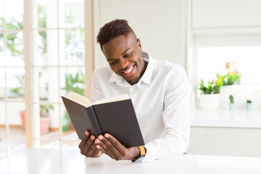Young african man reading a book, studying for univeristy smiling confident