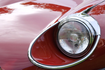 Obraz na płótnie Canvas Headlight and hood of retro red racing car ckose-up.
