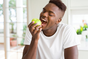 Young african american man eating a healthy green apple