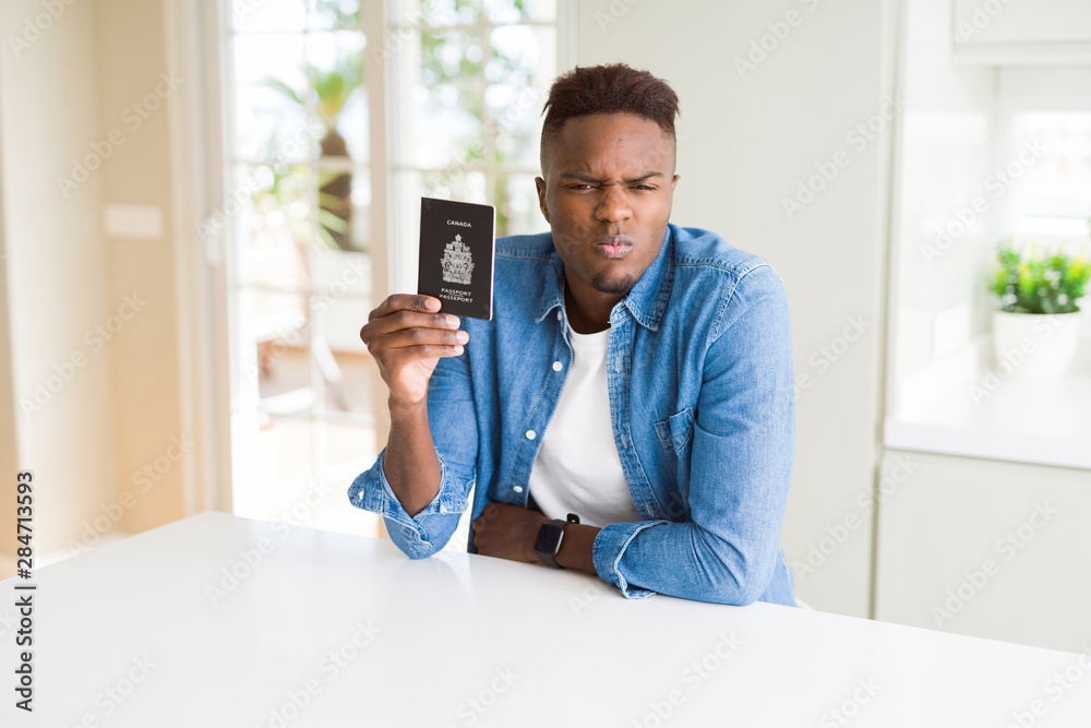 Poster African american man holding passport of Canada with a confident expression on smart face thinking serious