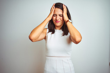 Young beautiful woman wearing dress standing over white isolated background suffering from headache desperate and stressed because pain and migraine. Hands on head.