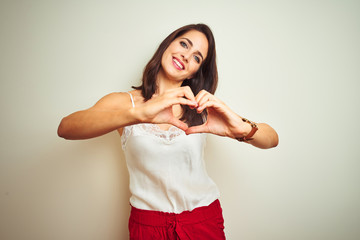 Young beautiful woman wearing t-shirt standing over white isolated background smiling in love doing heart symbol shape with hands. Romantic concept.