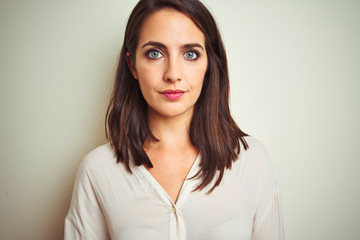 Obraz premium Young beautiful woman wearing casual shirt standing over white isolated background with serious expression on face. Simple and natural looking at the camera.