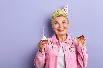 family has prepared unusual holiday, birthday for their favourite granny, isolated violet background, studio shot. copy space