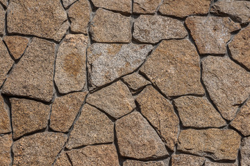 Beautiful horizontal texture of part of a natural granite stones wall in orange and gray hue is on the photo
