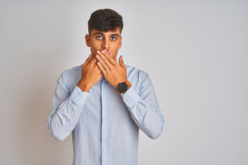 Young indian businessman wearing elegant shirt standing over isolated white background shocked covering mouth with hands for mistake. Secret concept.