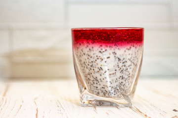 Greek yogurt and chia seeds for breakfast with raspberry sorbet. In a glass on a wooden white background.