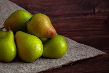 many pears lie on a wooden table and old linen cloth, daylight, green ripe sweet pears