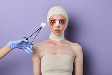 young serious injured girl waiting for surgical procedures. close up portrait, isolated blue background, studio shot.