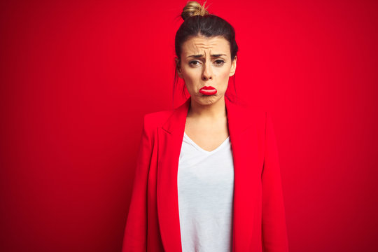 Young beautiful business woman standing over red isolated background depressed and worry for distress, crying angry and afraid. Sad expression.
