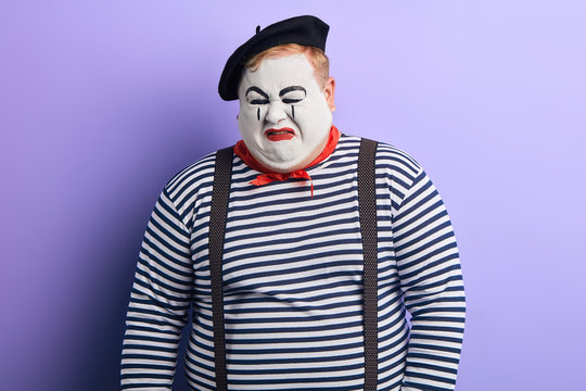 crying mime wearing striped sweater, beret. close up photo. negative feeling and emotion. facial expression