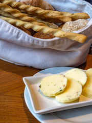 Bread and grissini in basket, butter with herbs and knife