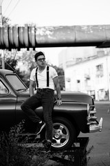 Guy in a shirt with suspenders posing at the retro car