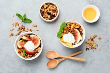 Figs with yogurt and honey oat granola on grey concrete background. Table top view. Healthy food