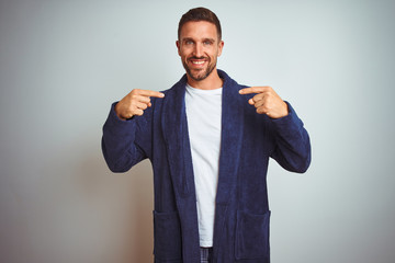 Young man wearing comfortable pajamas and robe at morning over isolated background looking confident with smile on face, pointing oneself with fingers proud and happy.